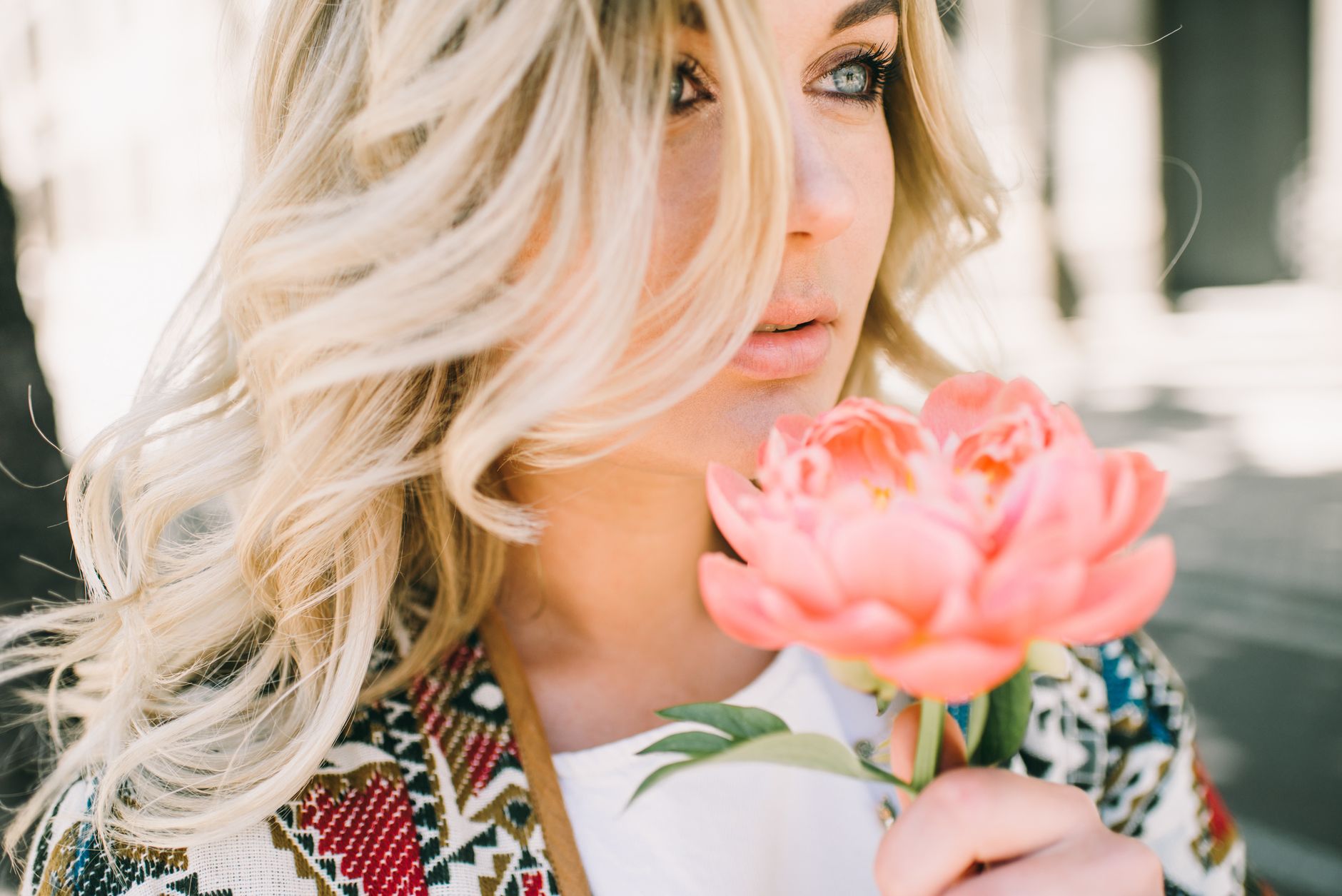 Close-up of a blonde woman holding a pink flower, showcasing beauty and nature. — MadNix Guide