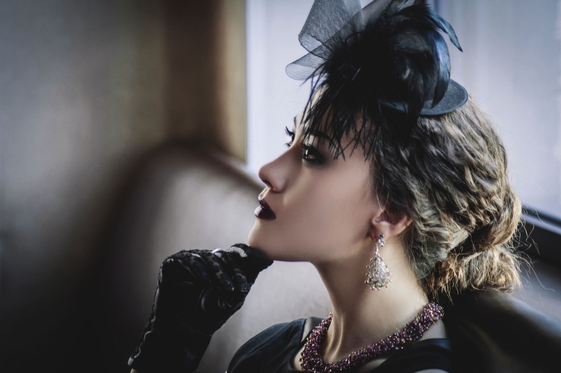 A stylish woman in a hat and jewelry, sitting indoors with a thoughtful expression. — NV Casino Guide