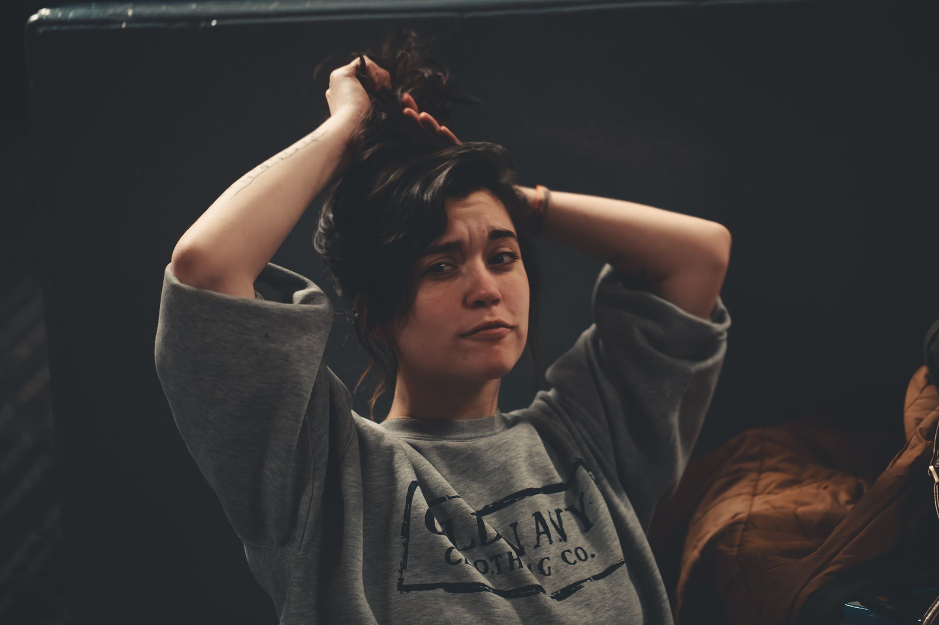 A candid portrait of a woman adjusting her hair indoors, showcasing natural beauty and casual style. — Test post title