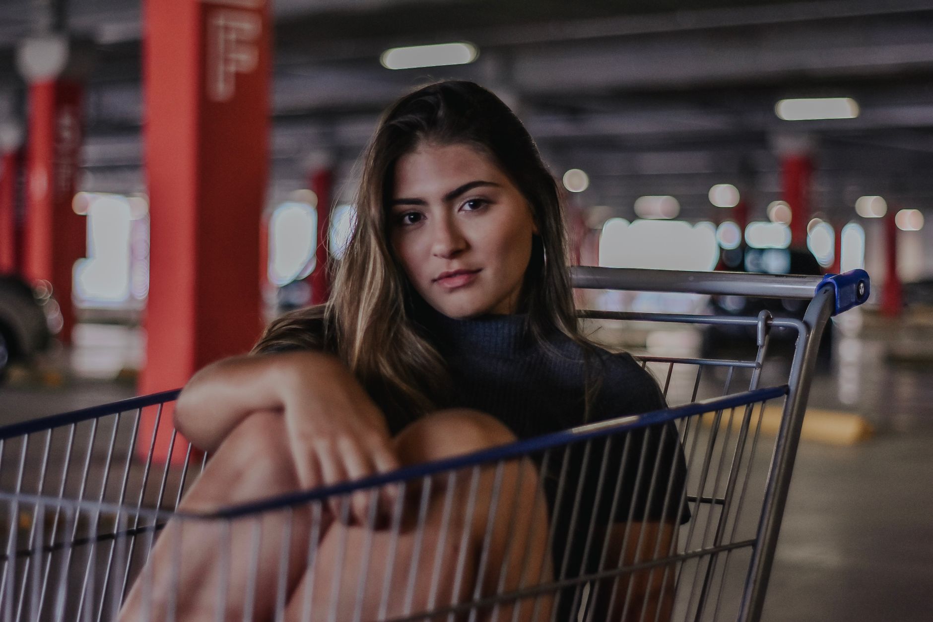 Portrait of a young woman sitting in a shopping cart inside a parking garage. — The Founding of YouTube A Short History